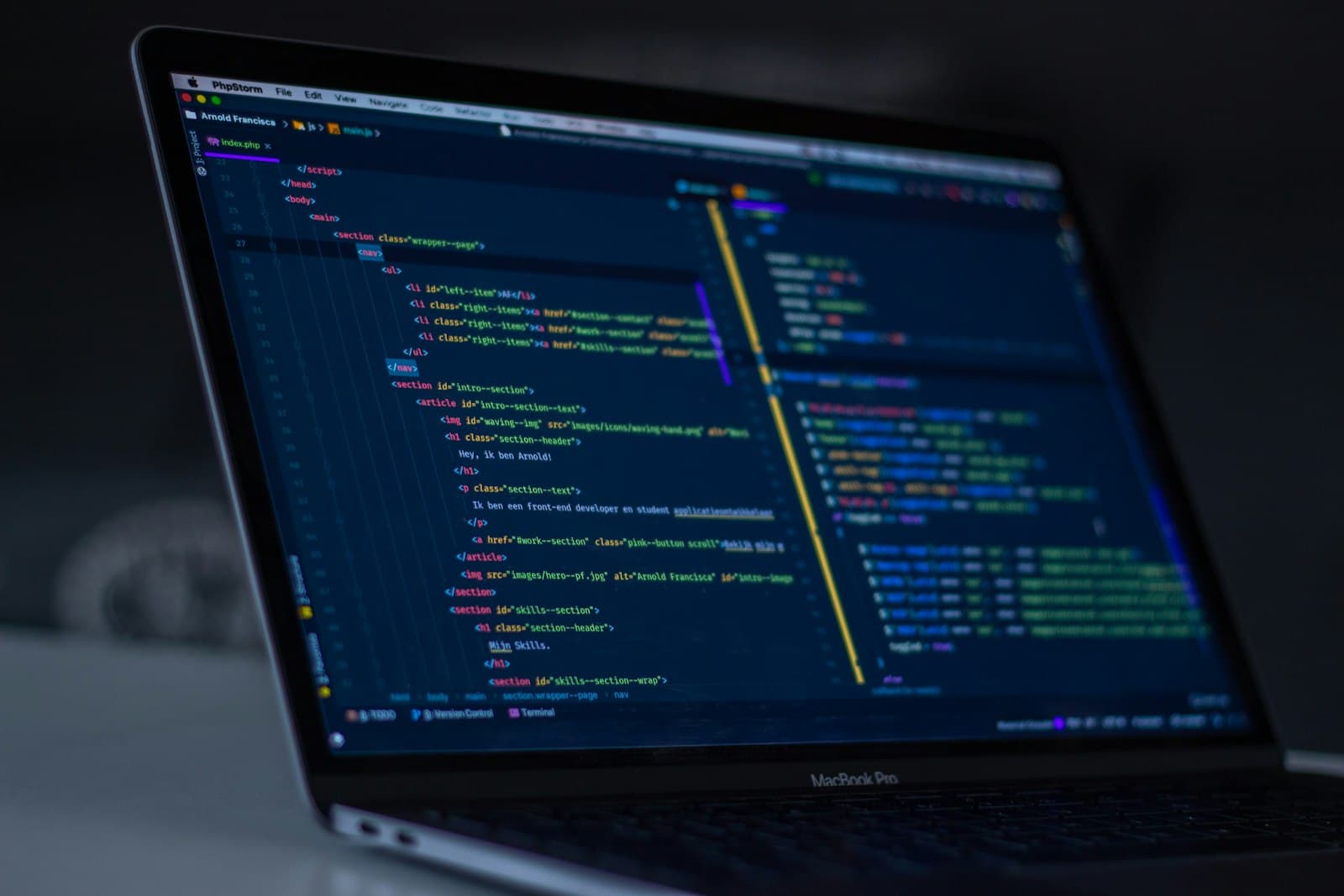 Karanlık bir ortamda, ekranında web sitesi kodu açık bir dizüstü bilgisayar